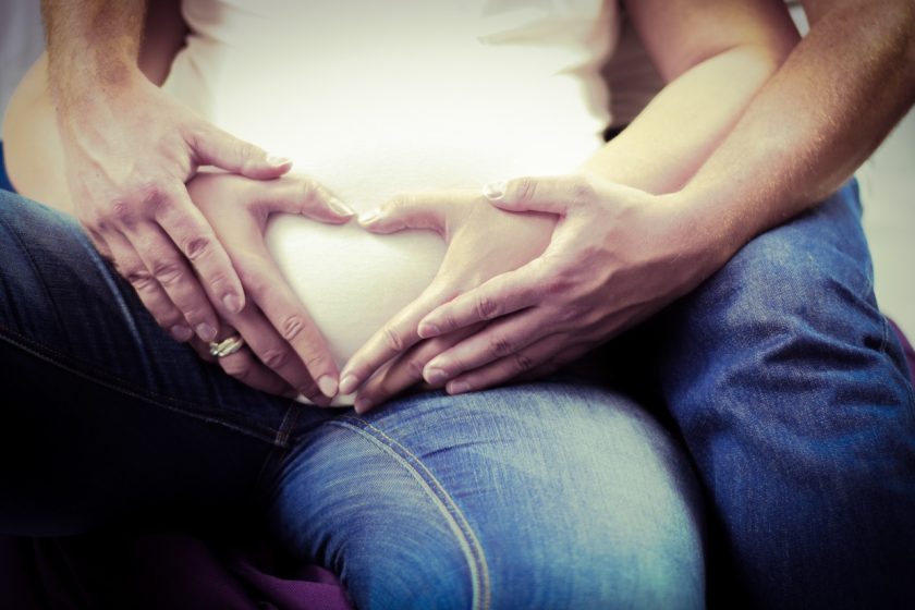 l’immagine rappresenta un uomo ed una donna che formano un cuore con le mani, felici perchè hanno calcolato la data presunta del parto