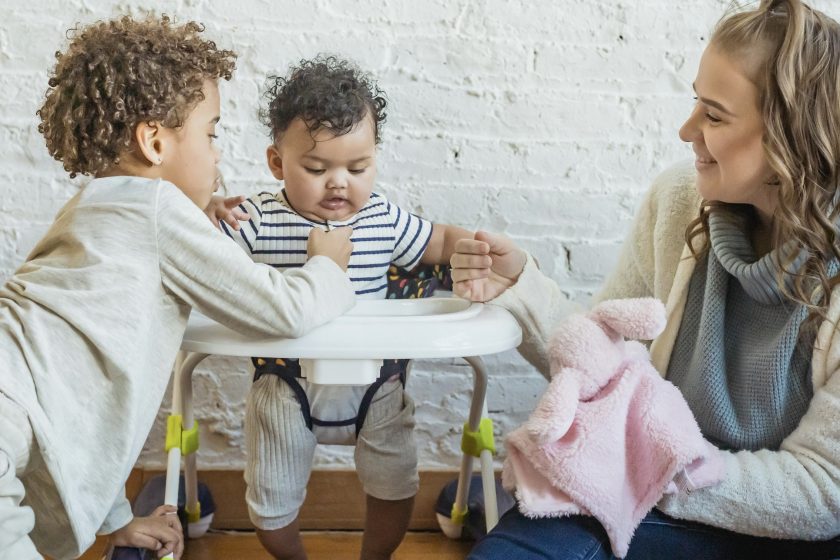 l’immagine rappresenta una mamma con i due figli, di cui uno è sul girello