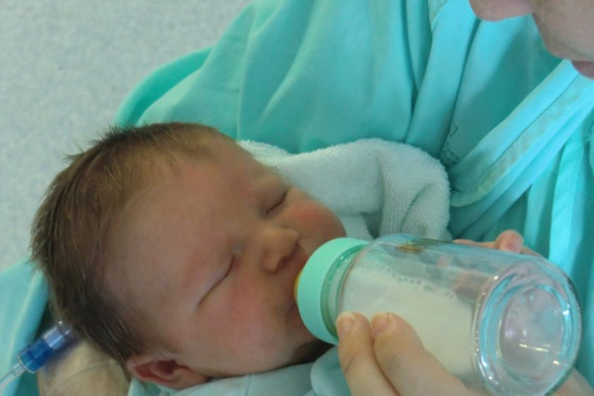 l’immagine rappresenta un neonato che viene allattato con del latte materno in biberon