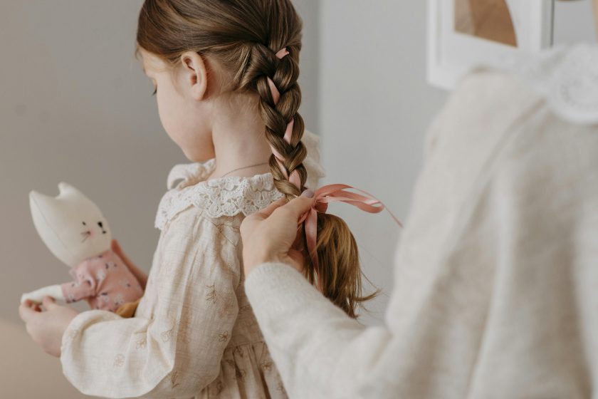 l’immagine rapresenta una madre che sta pettinando la figlia, acconciando i capelli sani e curati