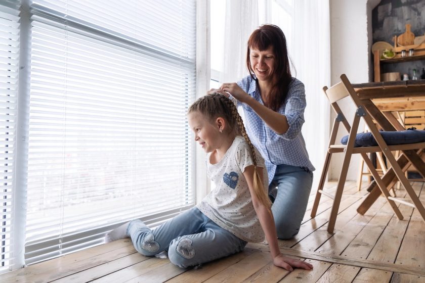 Madre controlla i capelli del bambino con pettine per individuare pidocchi e lendini