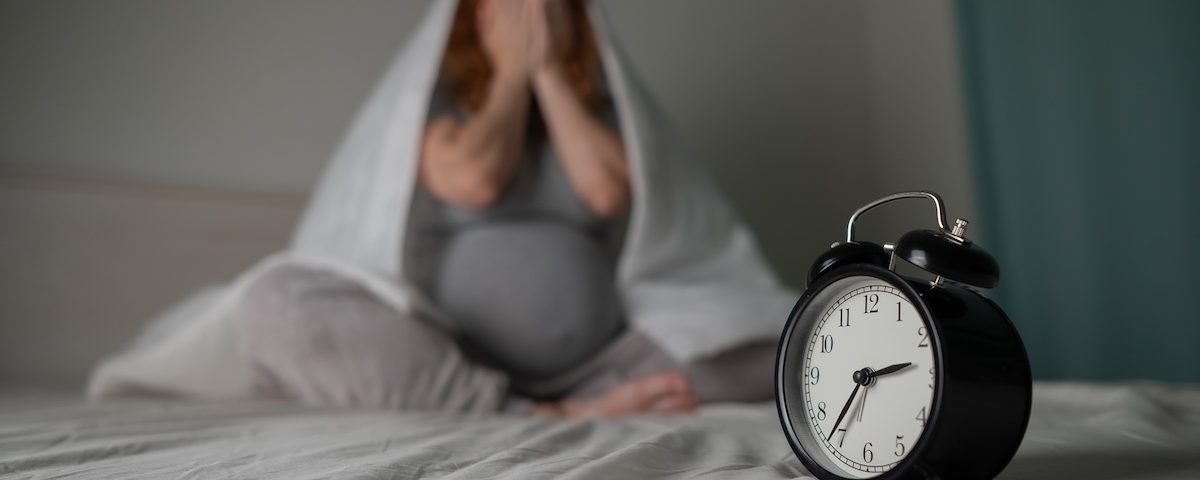 Donna incinta sdraiata nel letto durante la notte con difficoltà a dormire