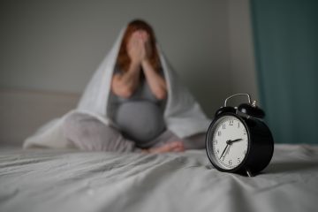 Donna incinta sdraiata nel letto durante la notte con difficoltà a dormire