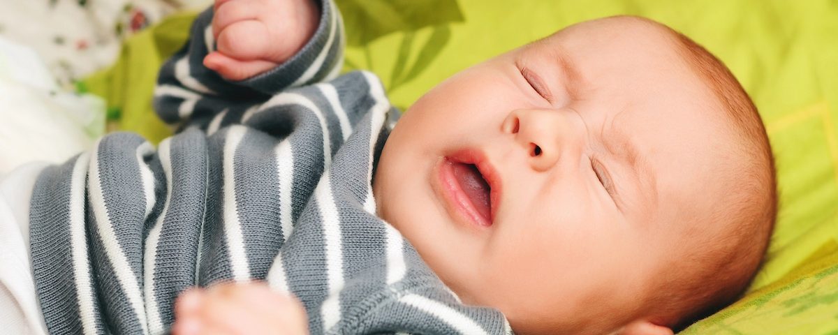 Neonato in primo piano mentre starnutisce in ambiente domestico