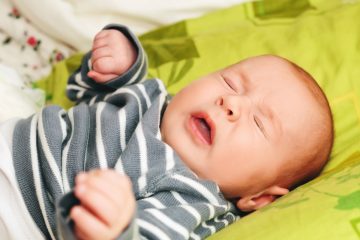 Neonato in primo piano mentre starnutisce in ambiente domestico