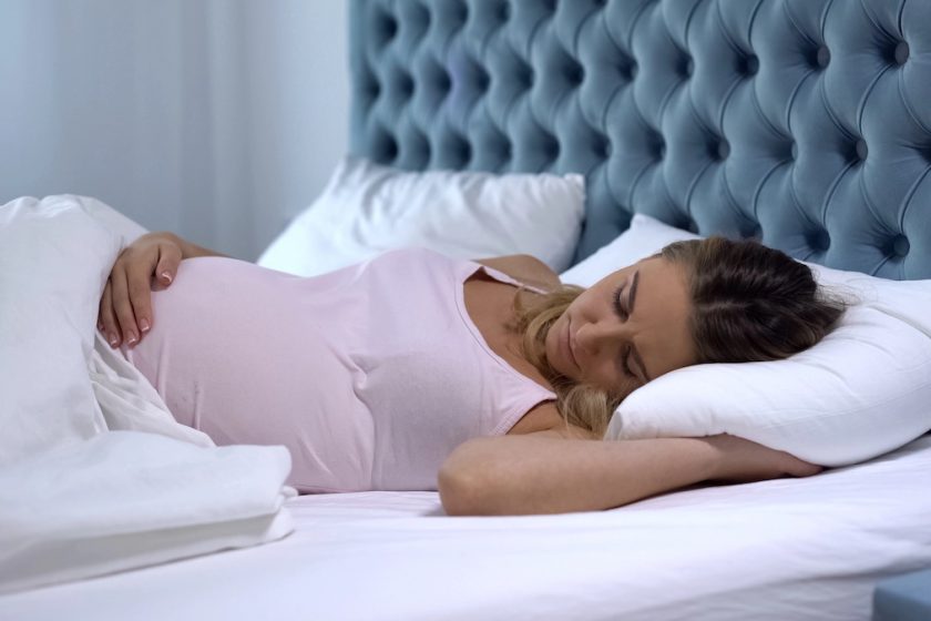 Donna incinta dorme su un fianco con cuscini di supporto per migliorare il sonno