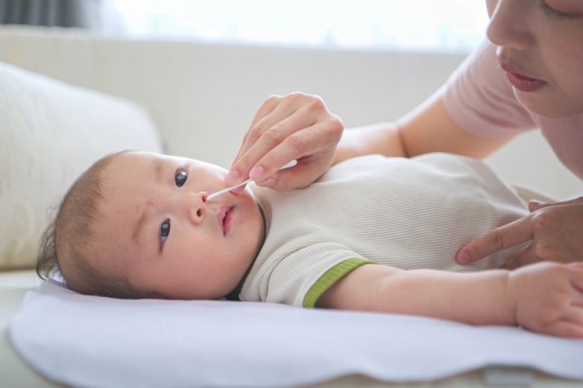 Genitore pulisce il naso del neonato con soluzione fisiologica