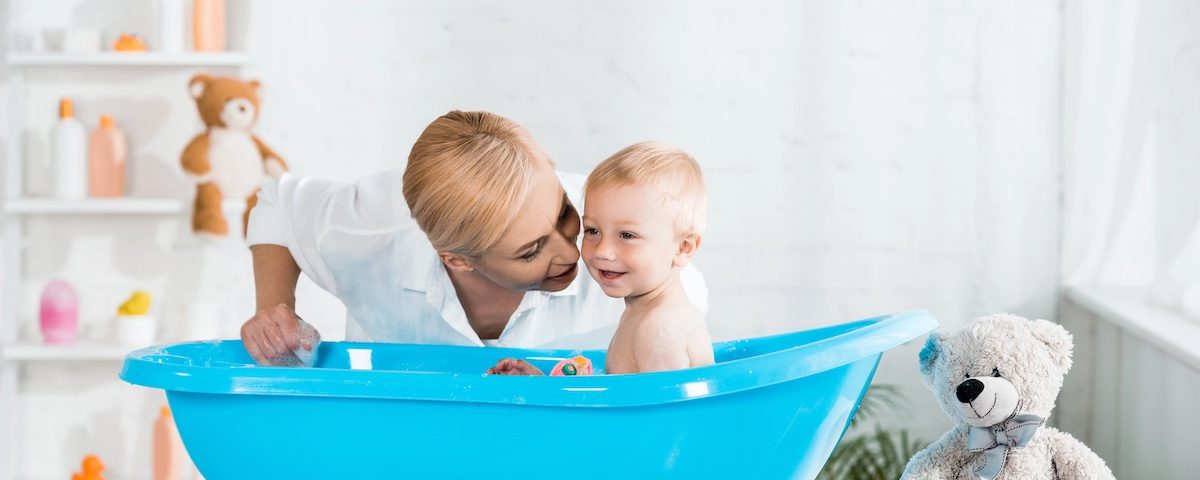 Genitore prepara asciugamano e detergente delicato per l’igiene di una bambina.