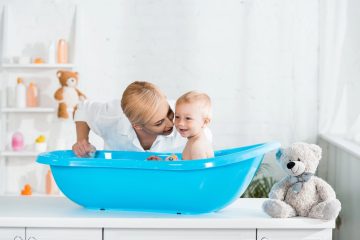 Genitore prepara asciugamano e detergente delicato per l’igiene di una bambina.