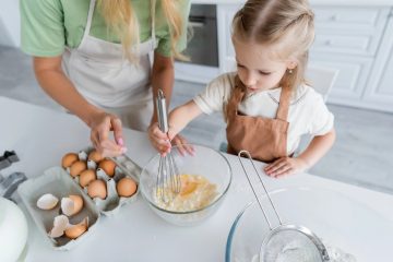 Genitore prepara una ricetta con uova in una cucina pulita, simbolo di sicurezza alimentare per bambini.