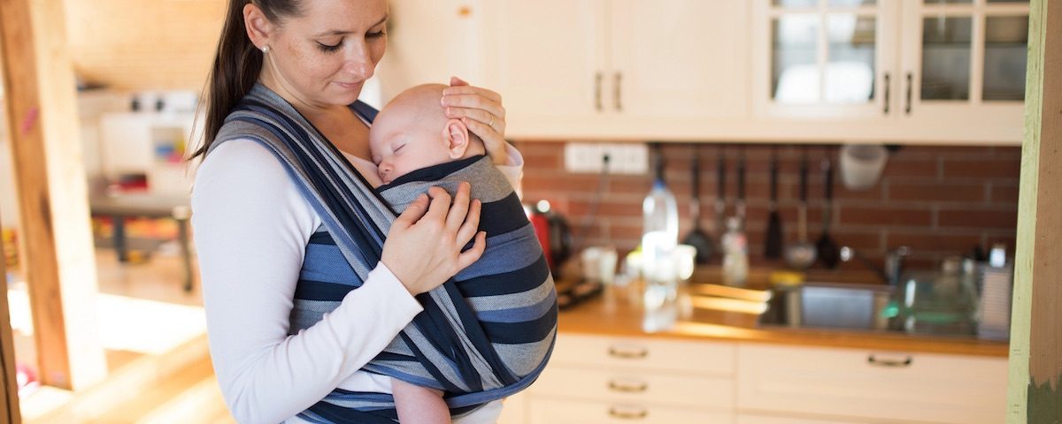 Mamma con neonato in un supporto porta bebè in tessuto naturale