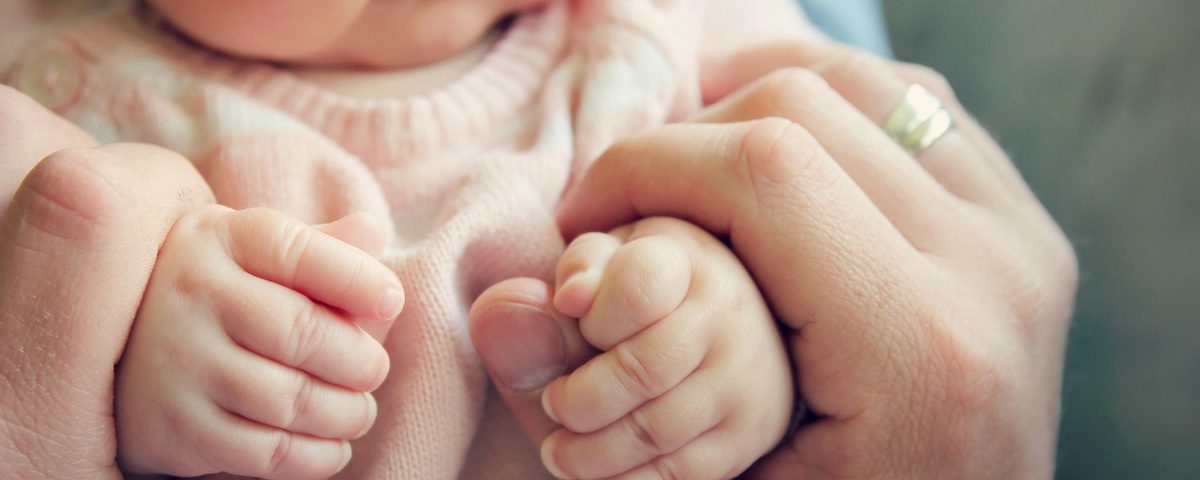 Neonato di 3 mesi che porta le mani alla bocca