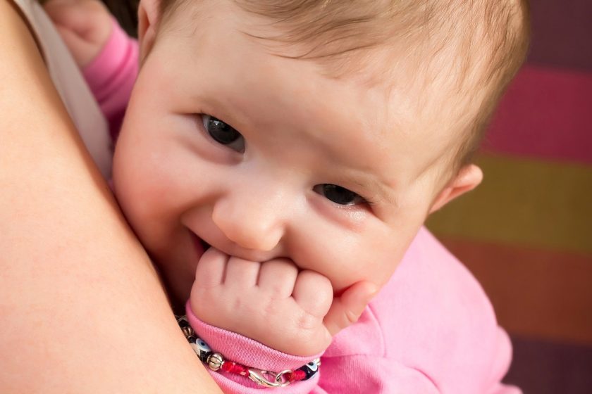 Mamma osserva il neonato di 3 mesi mentre porta il pugnetto alla bocca