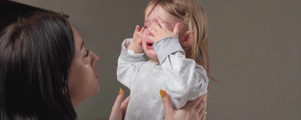 Genitore parla con calma a un bambino contrariato seduto sul tappeto