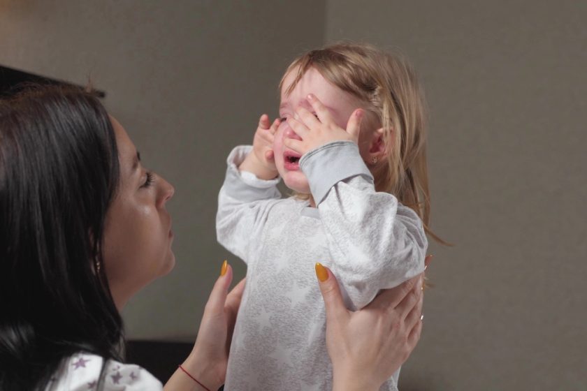 Genitore parla con calma a un bambino contrariato seduto sul tappeto