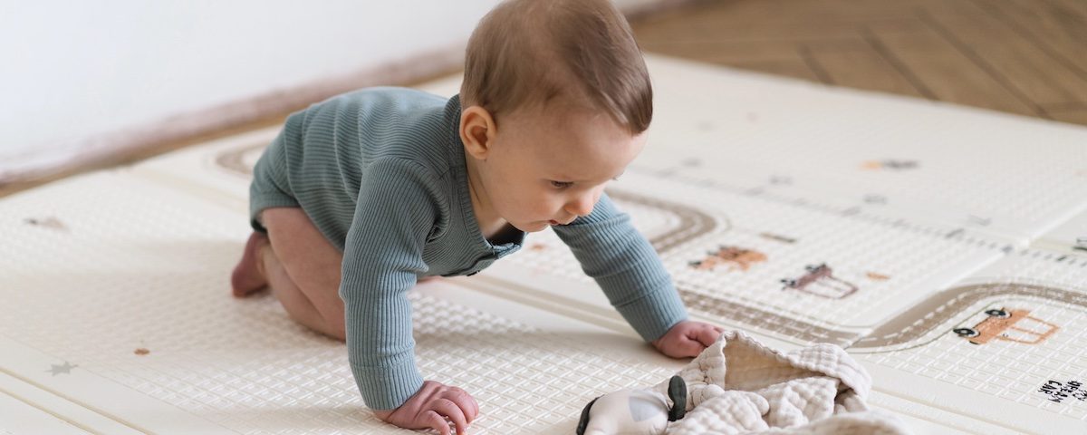 Neonato su tappeto morbido per bambini durante il gioco a terra