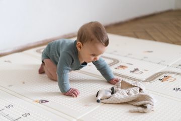 Neonato su tappeto morbido per bambini durante il gioco a terra