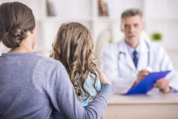 Pediatra spiega un referto a un genitore con bambino