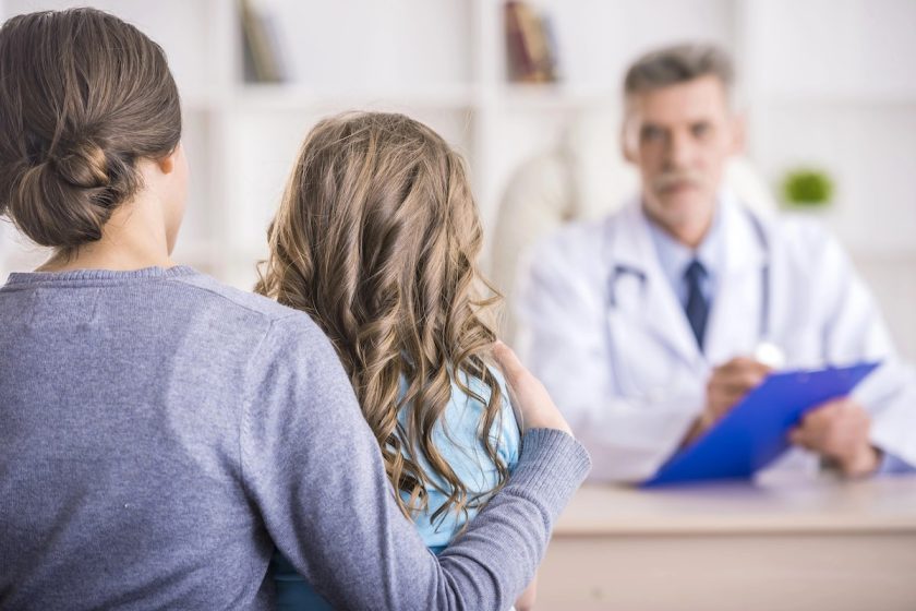Pediatra spiega un referto a un genitore con bambino